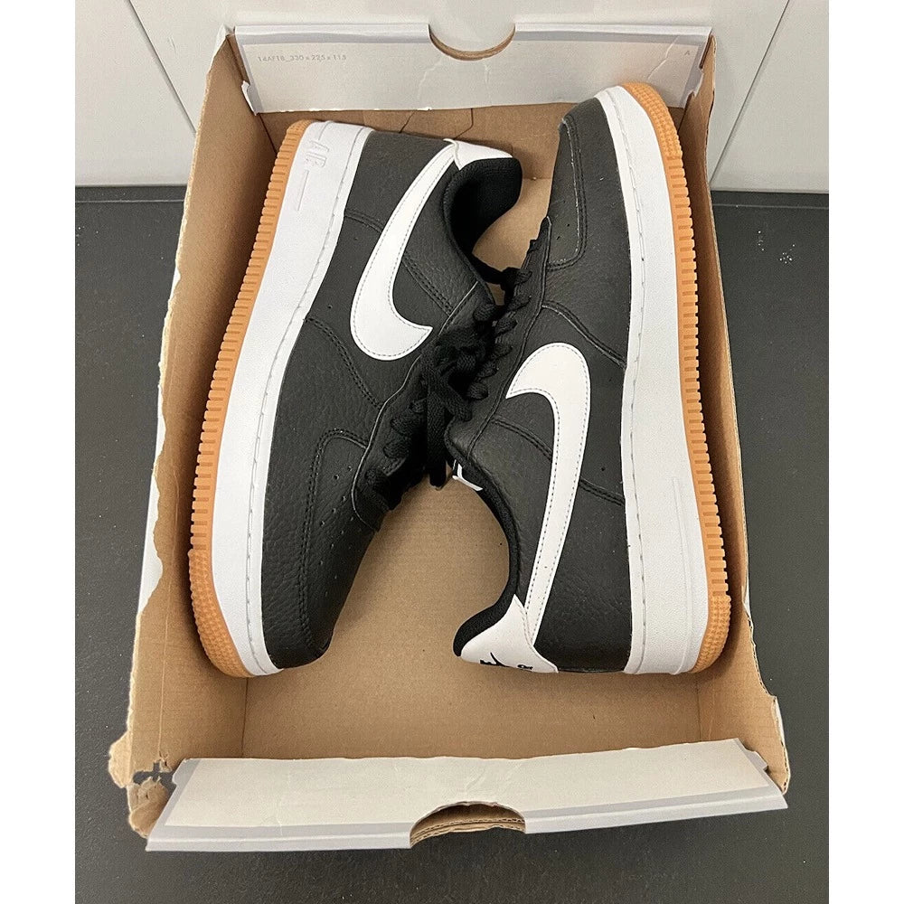 Hand holding black Nike Air Force 1 sneakers with white swoosh and gum sole