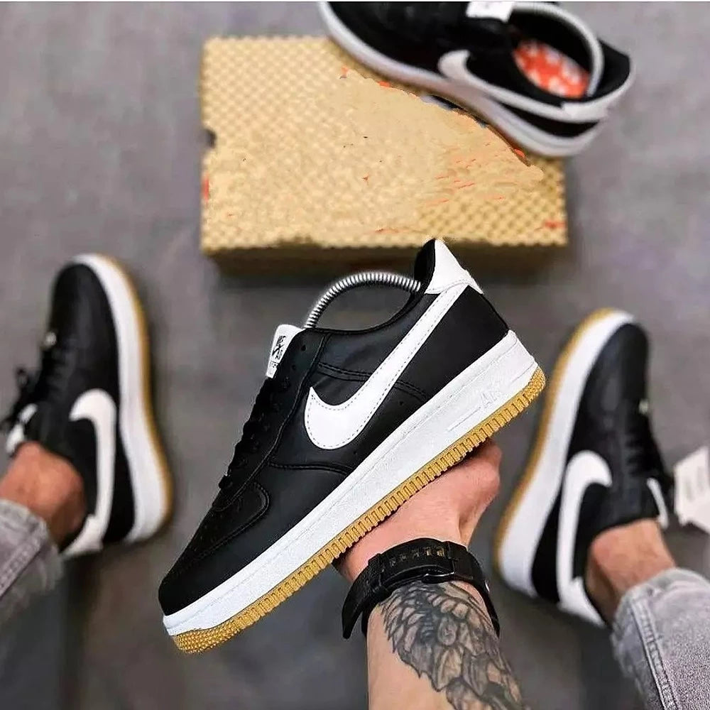 Hand holding black Nike Air Force 1 sneakers with white swoosh and gum sole